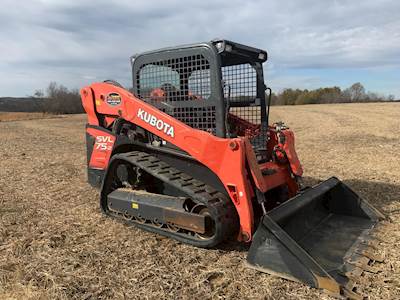 A man uses a 2018 Bobcat® MT55 to move some rocks while working outside on a mostly sunny day